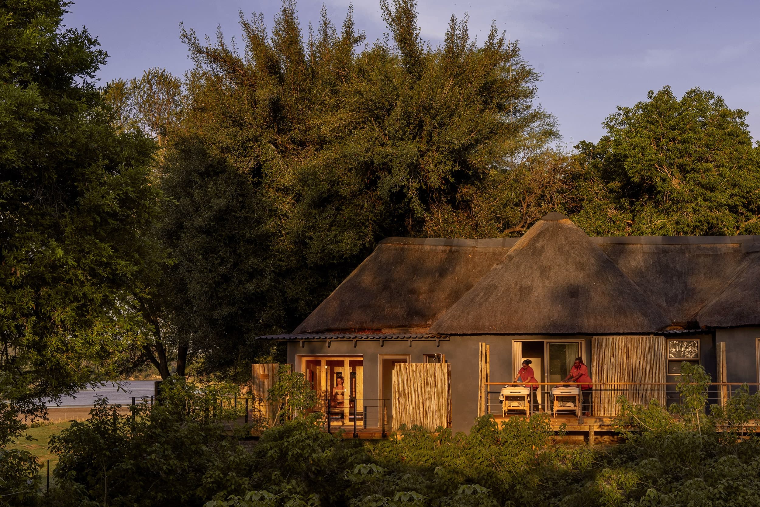 A thatched riverfront suite glowing at golden hour
